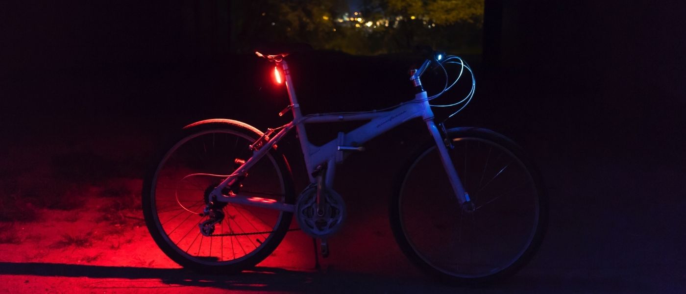 Photo d'un vélo dans la nuit avec une lampe arrière rouge allumée 